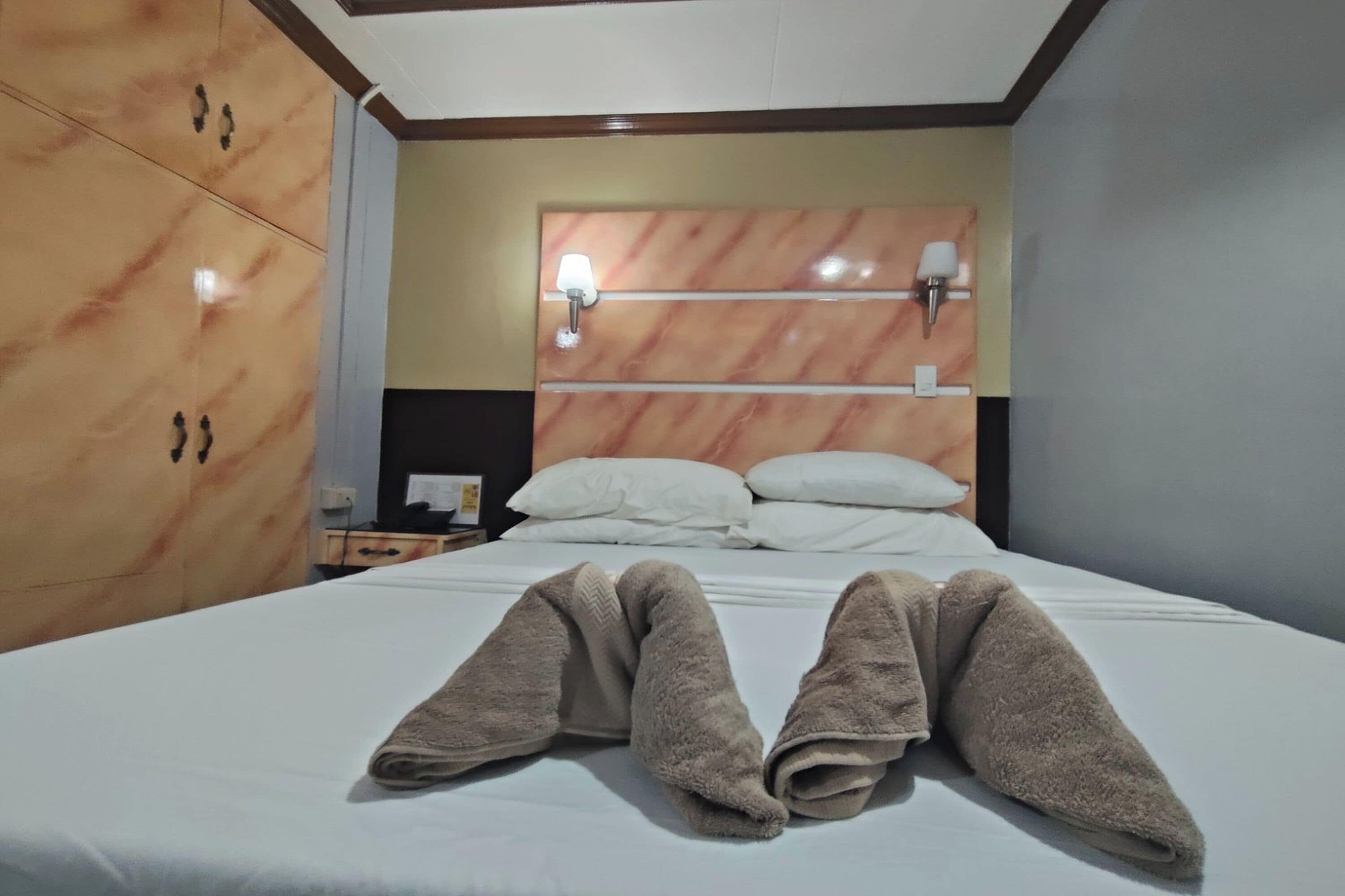Habitación de hotel con cama, mesita de noche y armario.