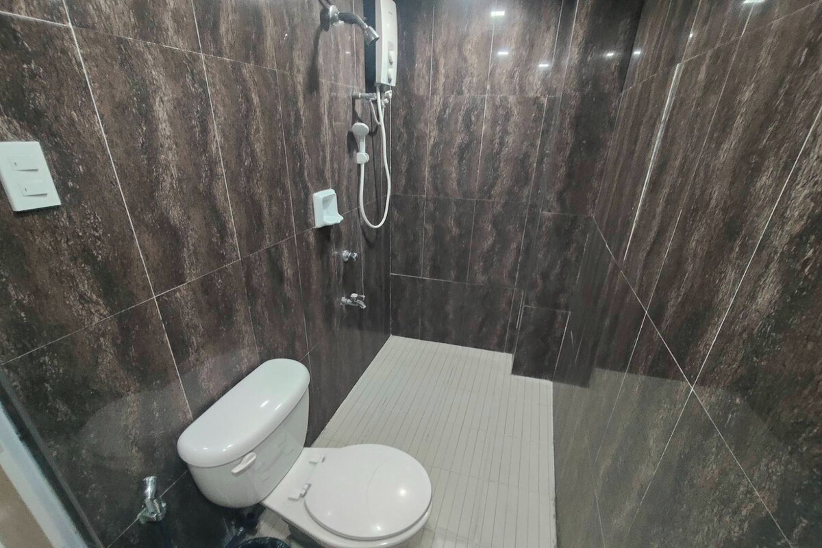Ein modernes Badezimmer mit Toilette, Dusche und Fliesenboden.