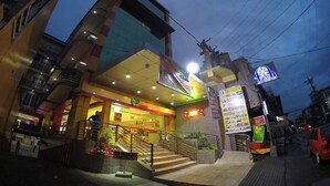 Un immeuble à plusieurs étages, doté d’une entrée bien éclairée, d’un escalier et d’un panneau indiquant l’accès au parking souterrain.