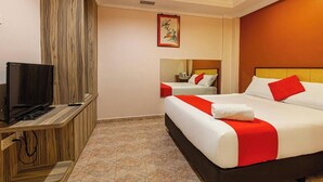 Une chambre d’hôtel avec un grand lit, un téléviseur posé sur une commode en bois et un tableau accroché au mur.