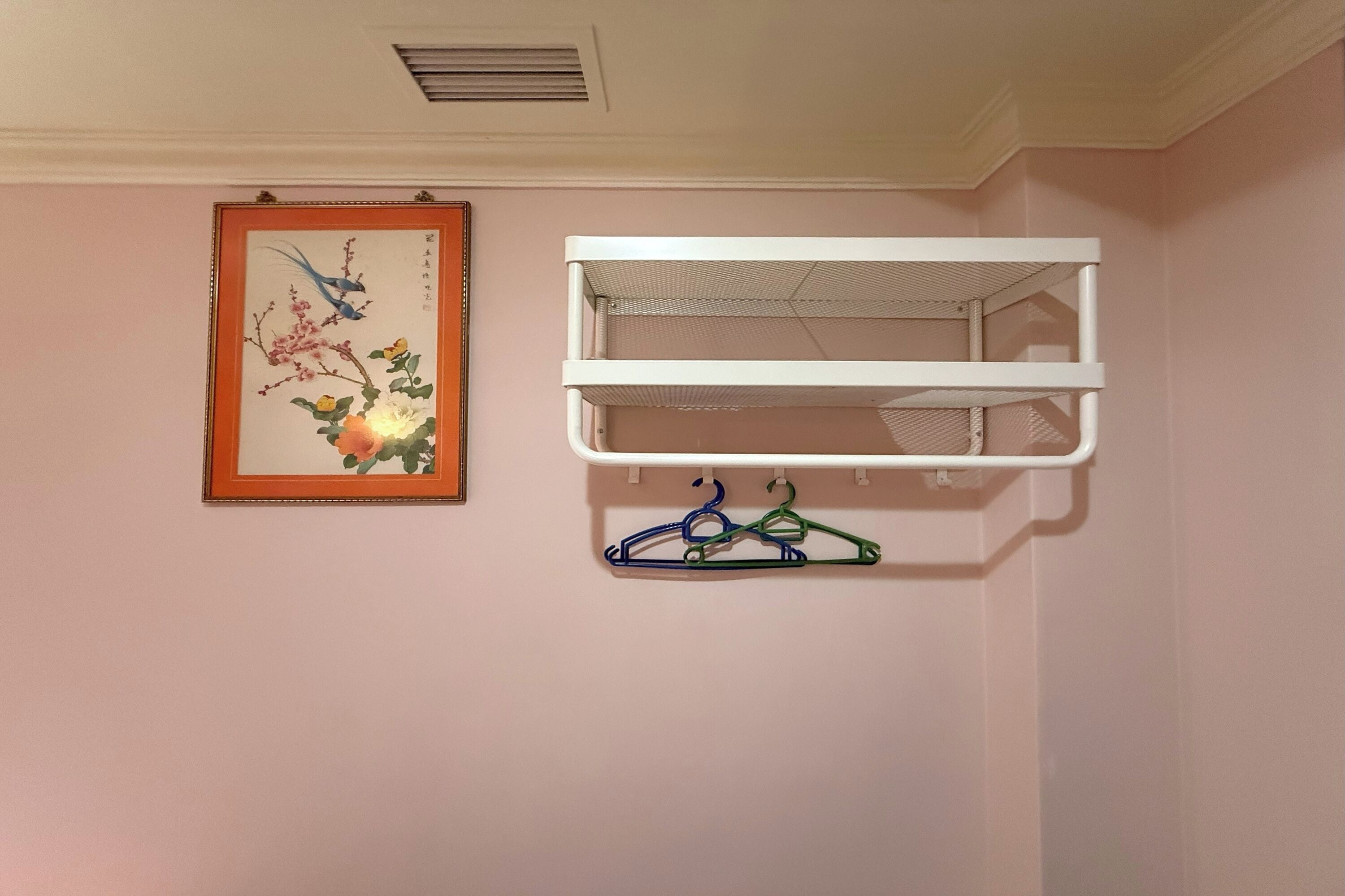 Una habitación con una estantería blanca y una obra enmarcada en la pared.