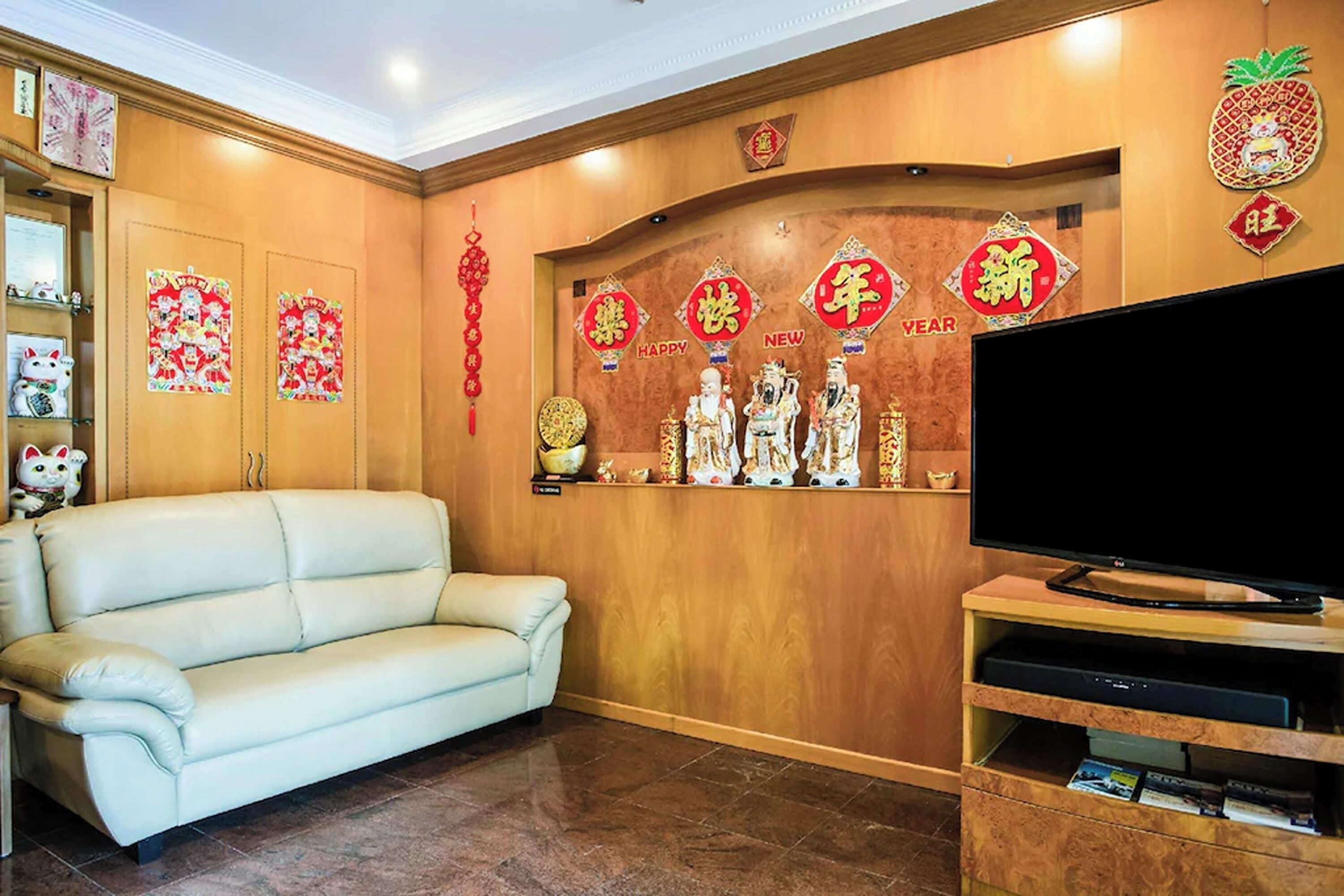 A living room with a sofa, television, and decorative wall with Chinese New Year symbols.