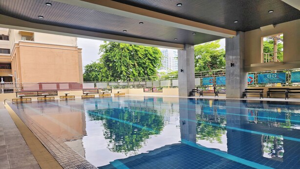 Una piscina con agua cristalina, solárium con azulejos y bancos.