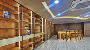 Un interior moderno con estanterías de madera, una zona de comedor con sillas e iluminación empotrada.
