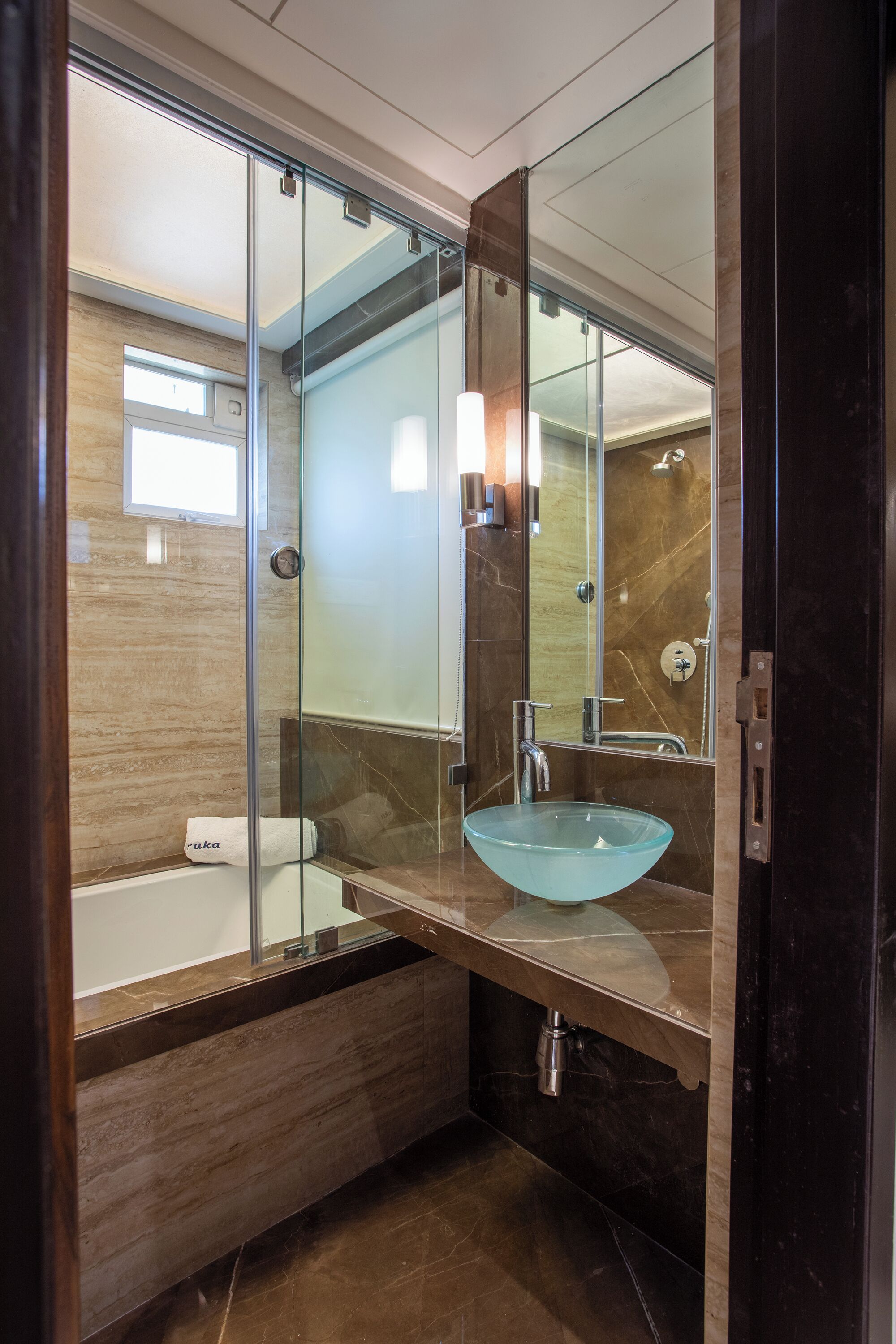 Une salle de bain moderne avec une douche à parois de verre, un lavabo en verre et un meuble-lavabo en bois.