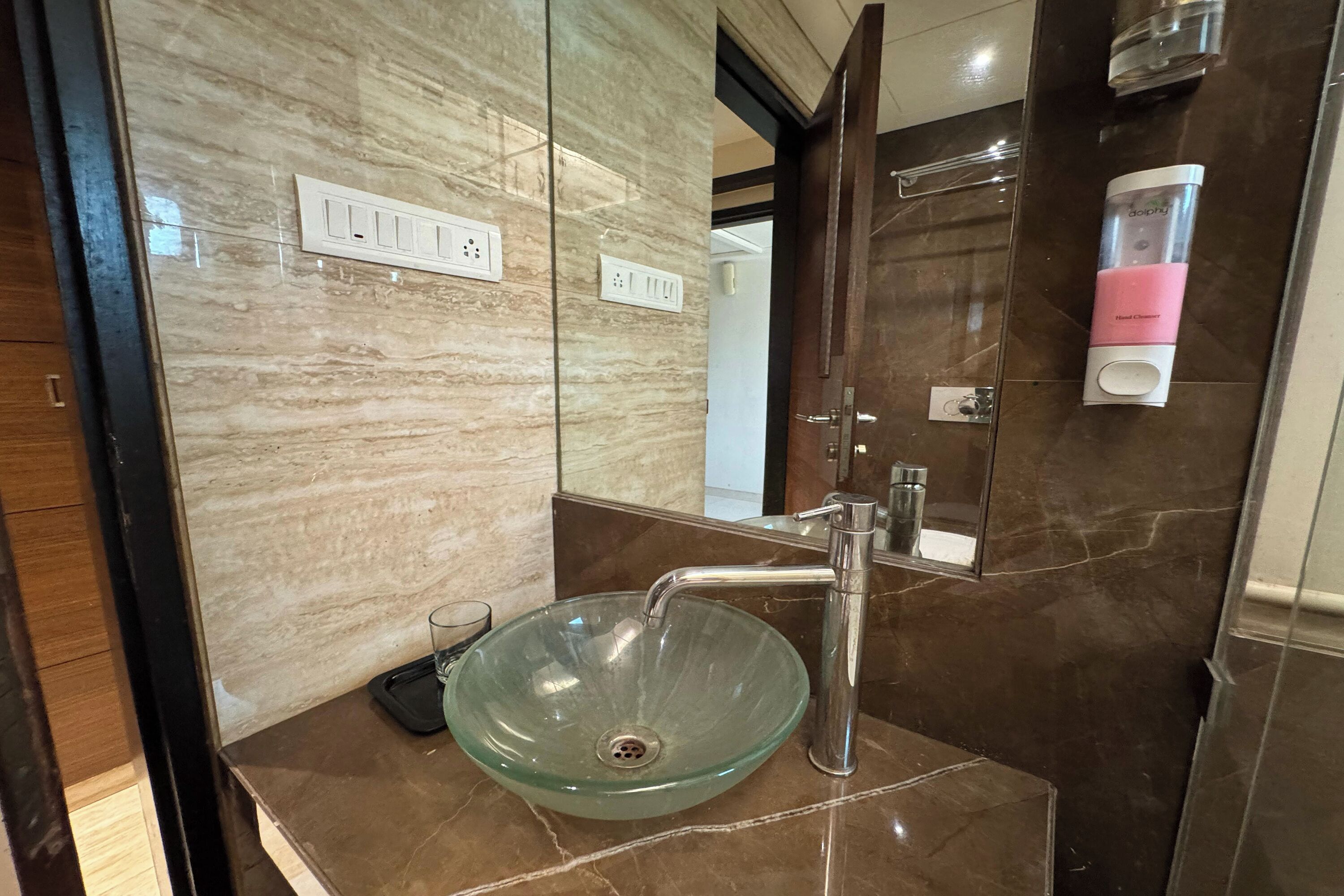 Un baño con un lavabo de vidrio, un grifo moderno y un dispensador de jabón.