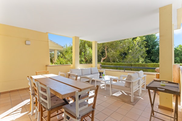 An outdoor patio with a dining table, chairs, sofas, and a small table with a bottle.