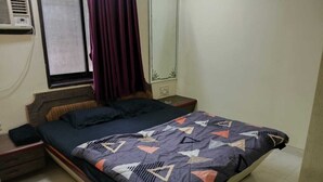 Una camera da letto con un letto, un comodino, uno specchio e una finestra con tende.