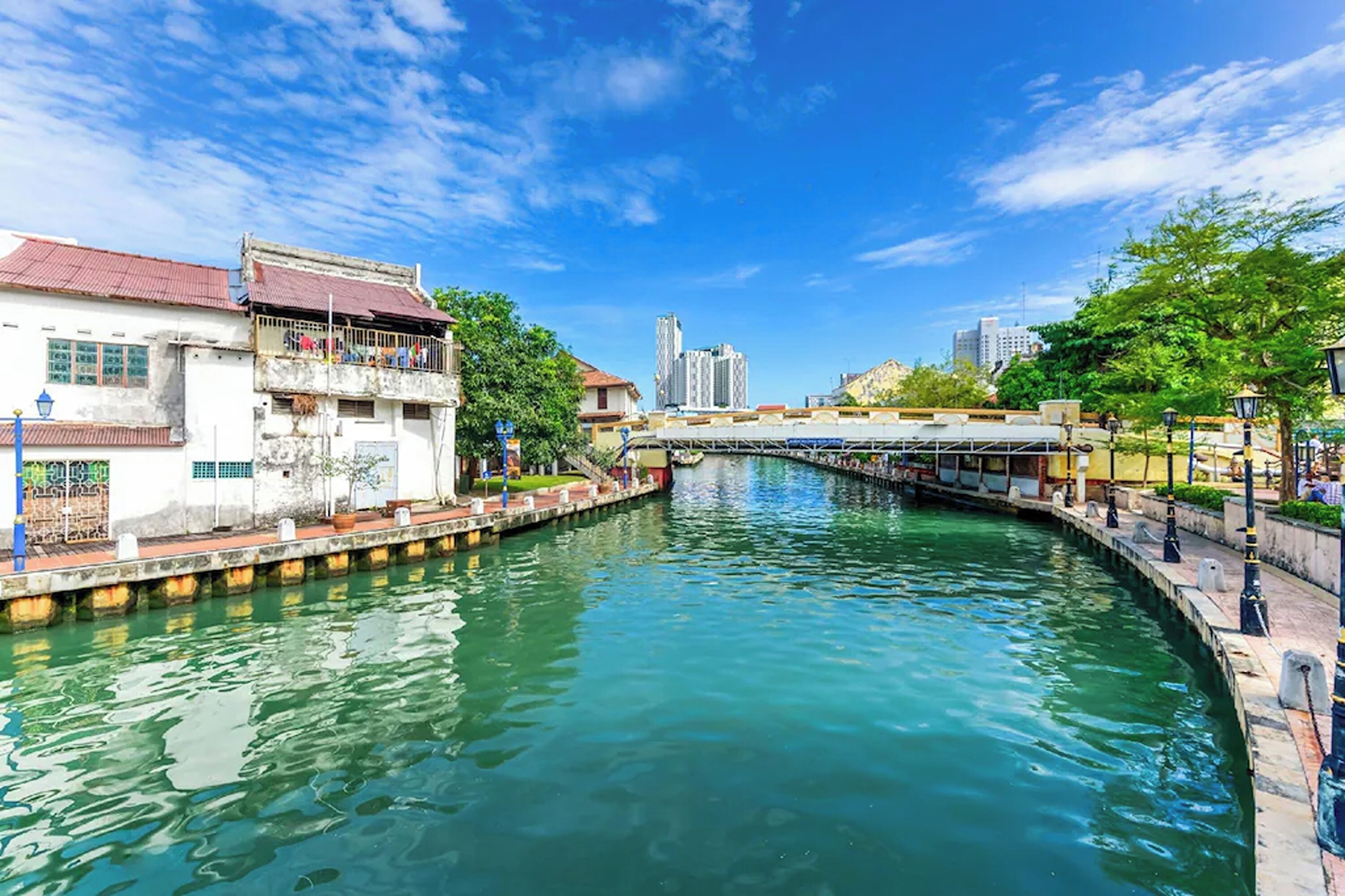 A canal with buildings on either side, a bridge in the background, and a clear sky.