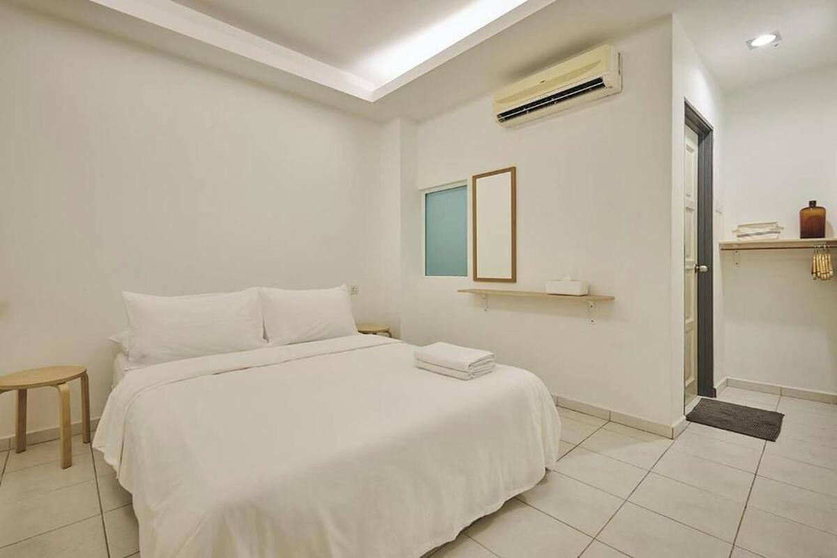 Hotelkamer met een bed, een klein nachtkastje, een wandairconditioner, een raam en een deur.