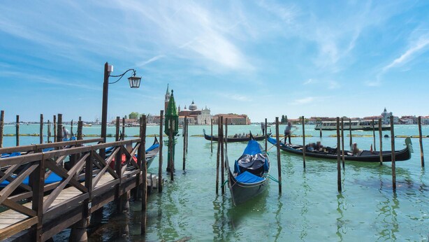 A wooden pier with gondolas docked in a canal, a historic building in the background, and a clear blue sky. - Lovely apartment in Chioggia with WiFi (Chioggia)