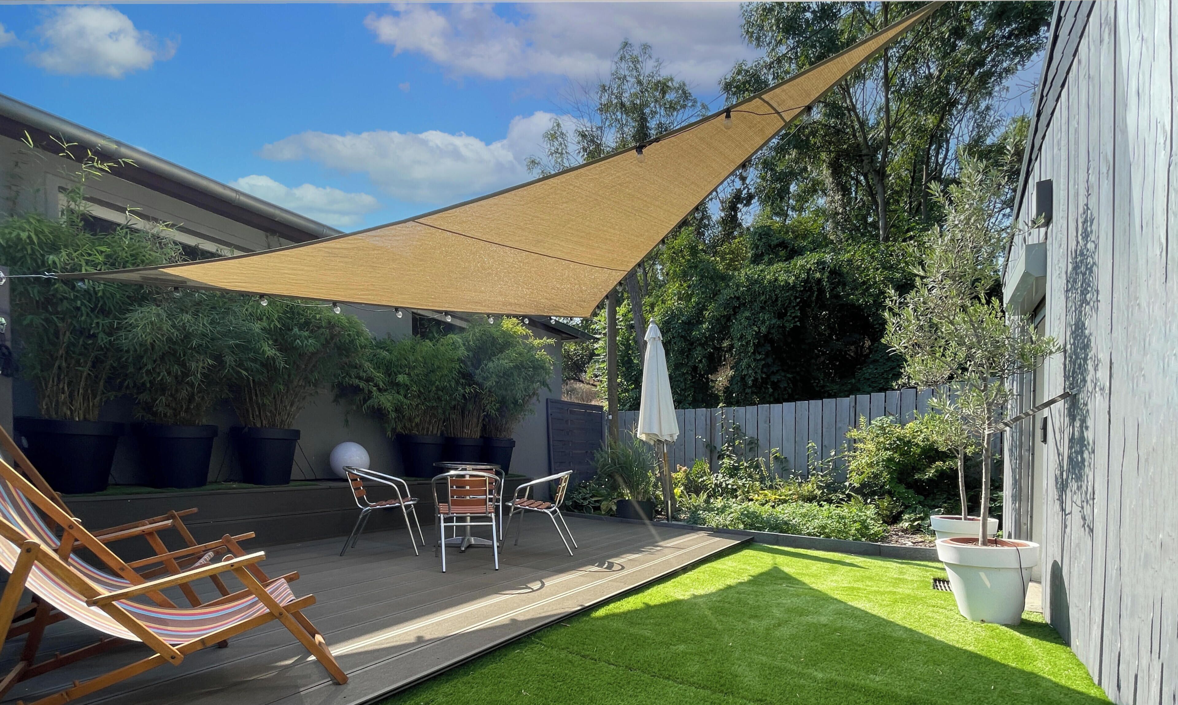 A patio with a wooden deck, a hammock, and a table with chairs.