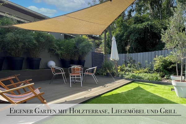 Aussenbereich mit Holzterasse Liegemöbeln und Grill