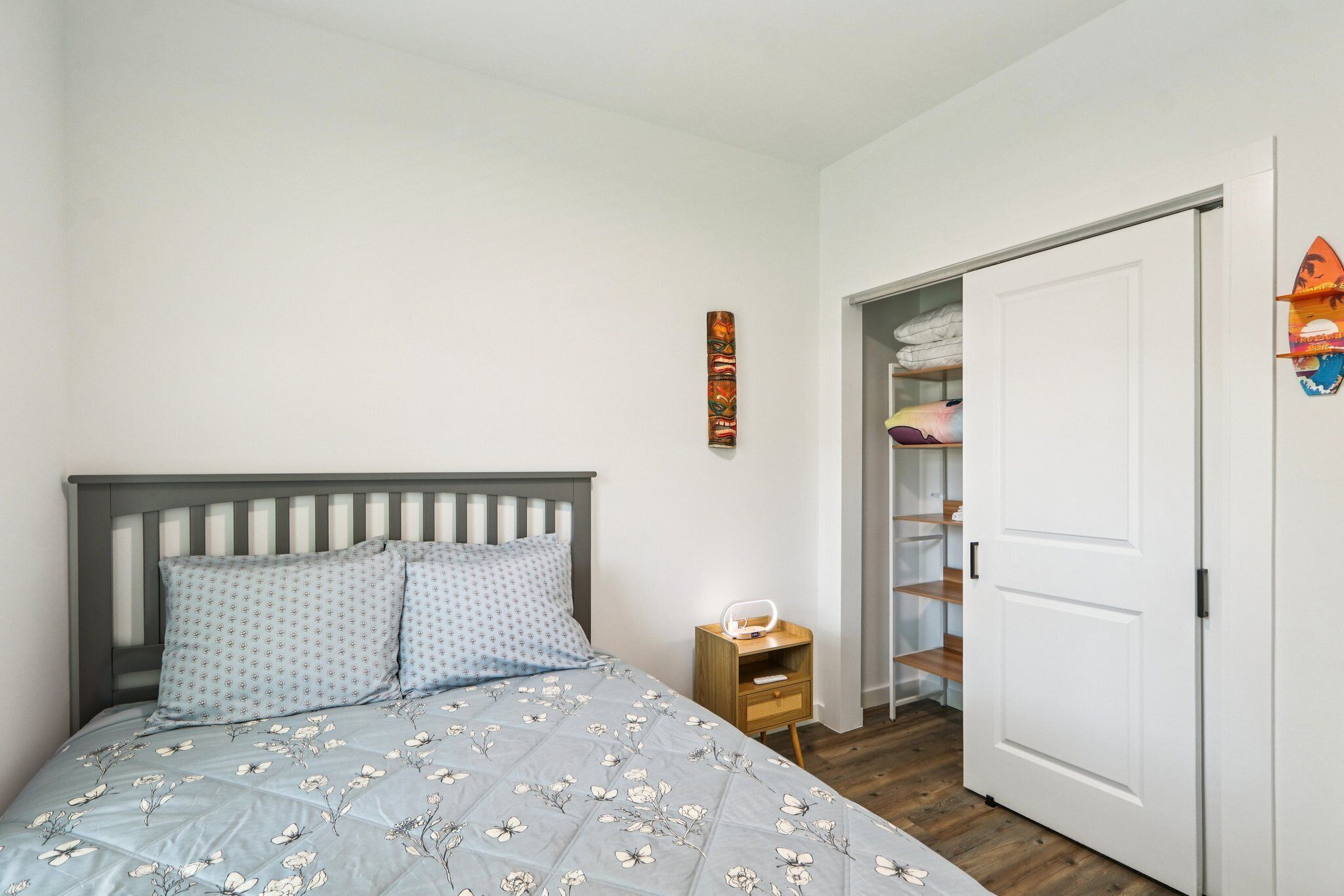 Un dormitorio con cama, mesita de noche, armario y un adorno en la pared.