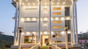Un grande edificio bianco con un ingresso imponente, colonne e un balcone con ringhiere.