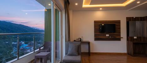A modern room with a balcony, a sofa, a coffee table, a TV mounted on the wall, and a wooden cabinet.