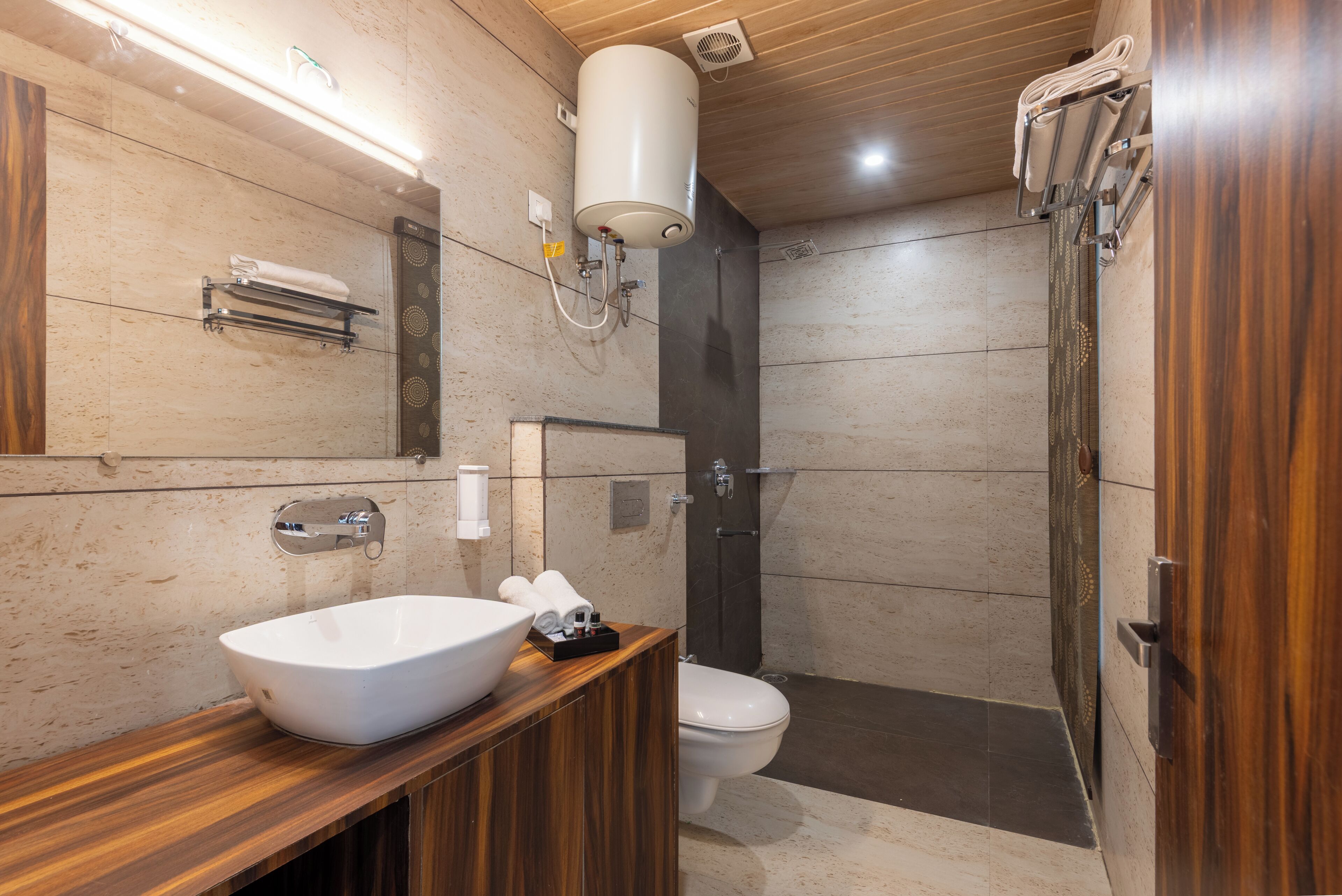 Une salle de bain moderne avec un meuble-lavabo en bois, un lavabo blanc, des toilettes et un espace douche.