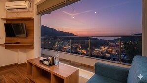 Un soggiorno moderno con una grande finestra che offre vista sulla città al tramonto.