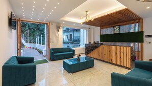 Una hall moderna con divani color acquamarina, un tavolino in vetro e una scrivania reception in legno.