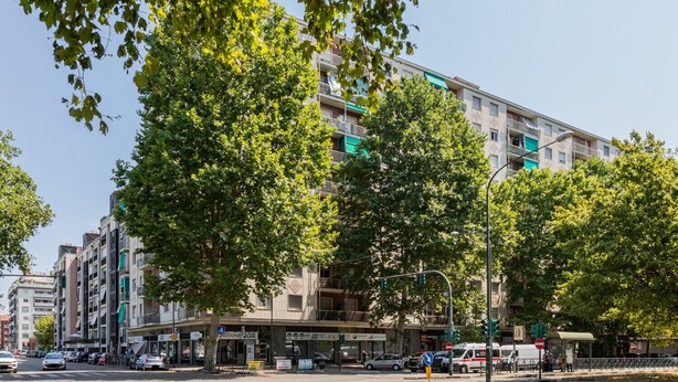 Et hotel med flere etager, altaner, en bar i stueplan og forskellige butikker i stueetagen.