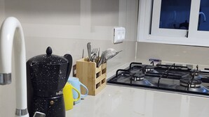Eine Küche mit einem Gasherd, einer Kaffeemaschine und einem Besteckhalter.