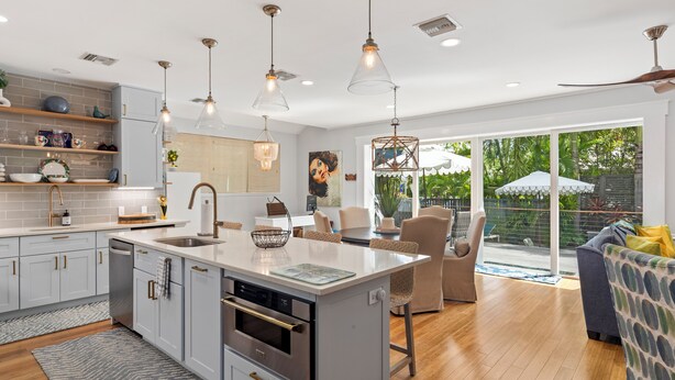 Een moderne keuken met een centraal eiland, inbouwapparatuur en hanglampen.