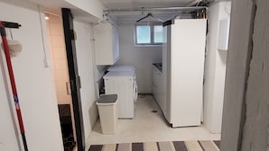 Une cuisine de taille réduite, avec des appareils électroménagers blancs, une petite fenêtre et un sol à rayures.