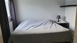 Une chambre d’hôtel avec un lit, une table de chevet avec une lampe et un panneau de commande.