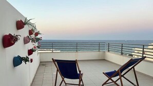 A balcony with two folding chairs, a tiled floor, and a railing. - Luxurious sea view (Sousse)