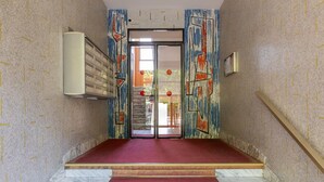 Una escalera con un suelo rojo que lleva a una puerta con un panel de vidrio.