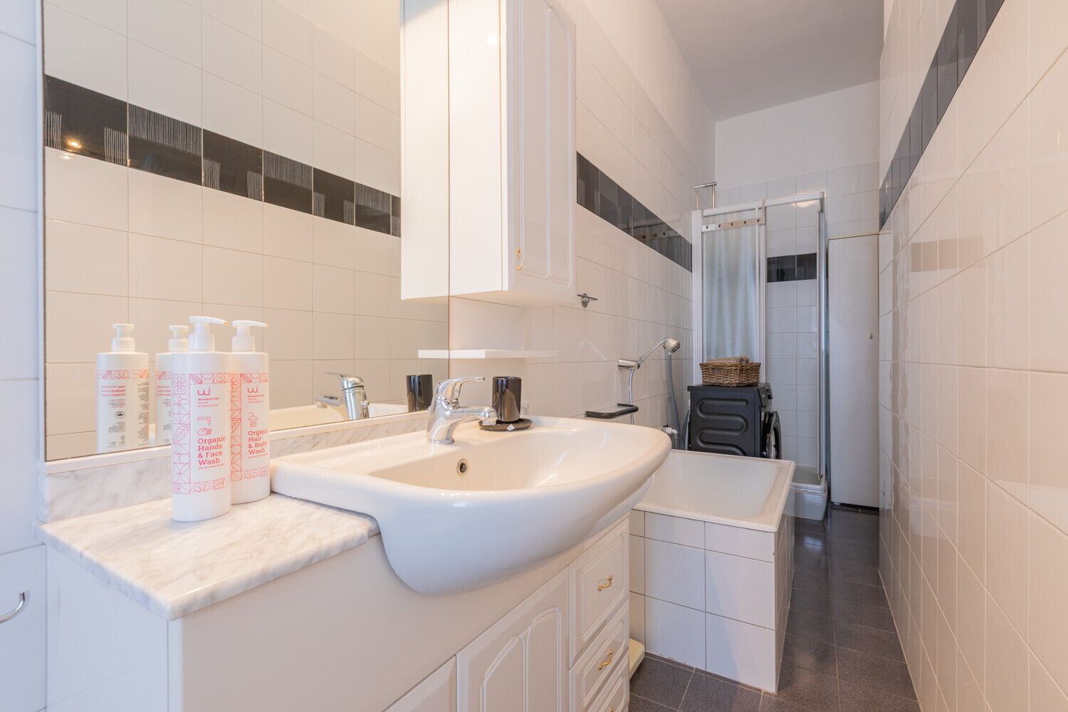 Een moderne badkamer met een groot wastafel, spiegel en toiletartikelen.