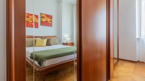 Un dormitorio con una cama de madera, una mesita de noche y dos cuadros colgados en la pared.
