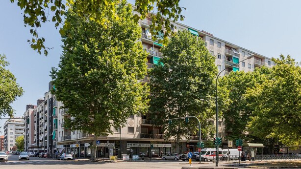 Un hotel de varios pisos con balcones, un bar en la planta baja y diversas tiendas en la planta principal.