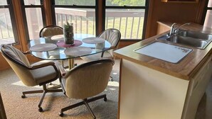 A kitchen with a glass-top table, chairs, a sink, and a view of the outdoors. - Eagle River Northwoods Retreat - 3 Bedrooms - 2 Bathrooms (Eagle River)