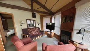 A cozy living room with a sofa, two armchairs, a television, a fireplace, and a small table with a lamp. - Eagle River Northwoods Retreat - 3 Bedrooms - 2 Bathrooms (Eagle River)