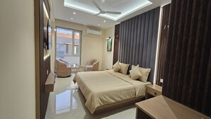 A modern bedroom with a large bed, a ceiling fan, and a view of the outside through a window. - Hotel Star Square (Indore)