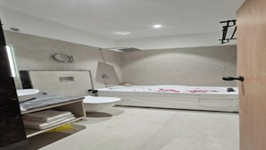 A modern bathroom with a bathtub, two sinks, and a toilet. - Hotel Star Square (Indore)