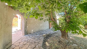 Un sendero de piedra que conduce a un edificio con puerta de madera, rodeado de vegetación.