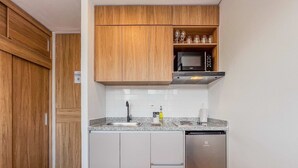 Une cuisine compacte dotée de meubles en bois, d’un four à micro-ondes encastré, d’un évier en acier inoxydable et d’un lave-vaisselle.