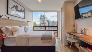 Une chambre d’hôtel moderne, dotée d’un grand lit, d’un bureau et d’une télévision.