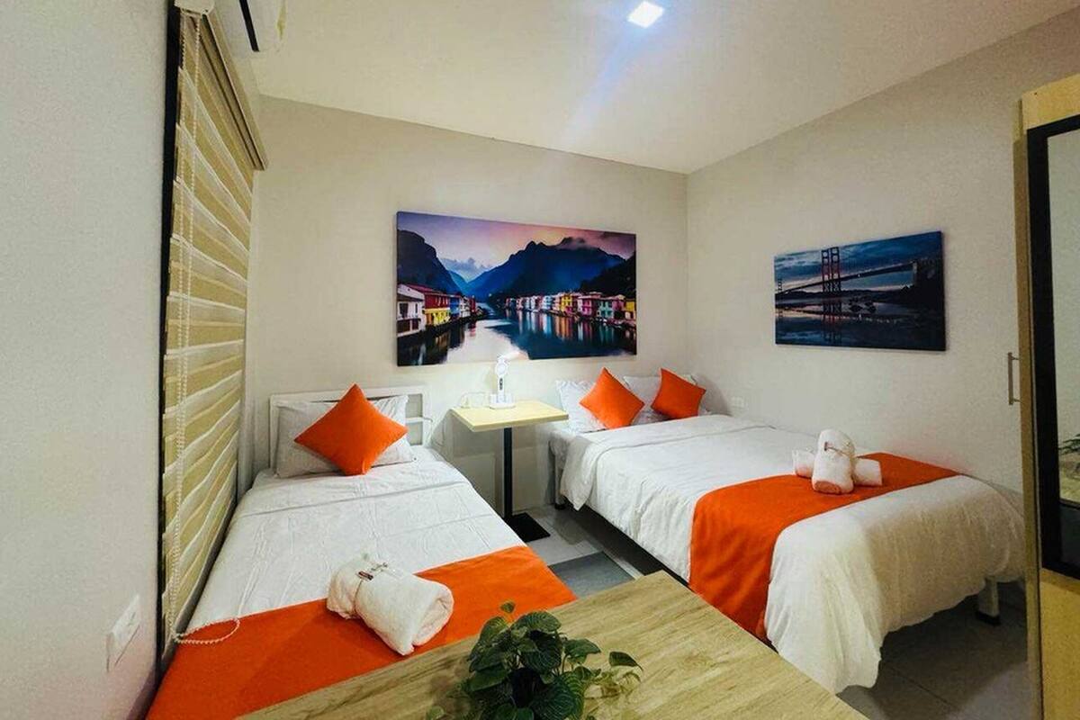 Een hotelkamer met twee bedden, een kleine tafel en twee schilderijen aan de muur.