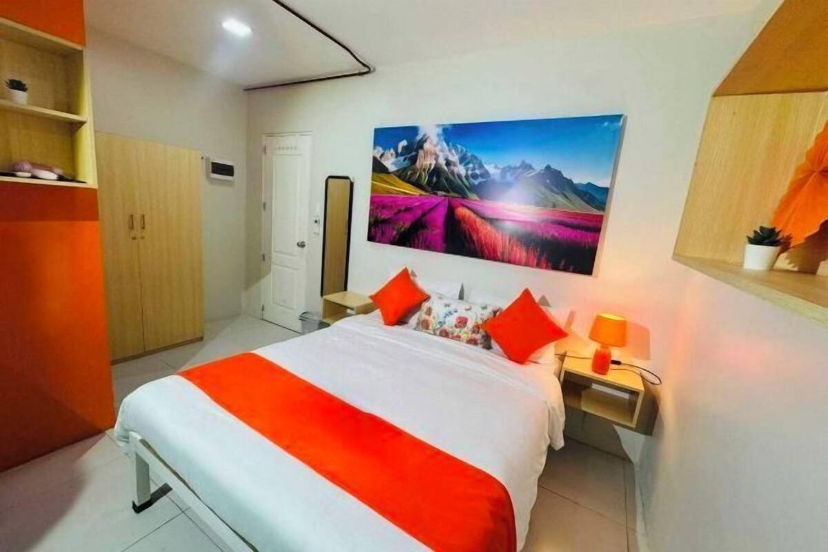 Een hotelkamer met een bed, een nachtkastje, een aan de muur hangend schilderij, een kledingkast en een plank met een potplant.