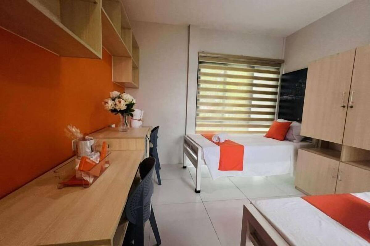 Een kleine hotelkamer met een bed, een bureau, een stoel, een televisie en een raam met zonwering.