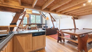 Une cuisine moderne avec des meubles en bois, un lave-vaisselle et un coin repas comprenant une table et des bancs en bois.