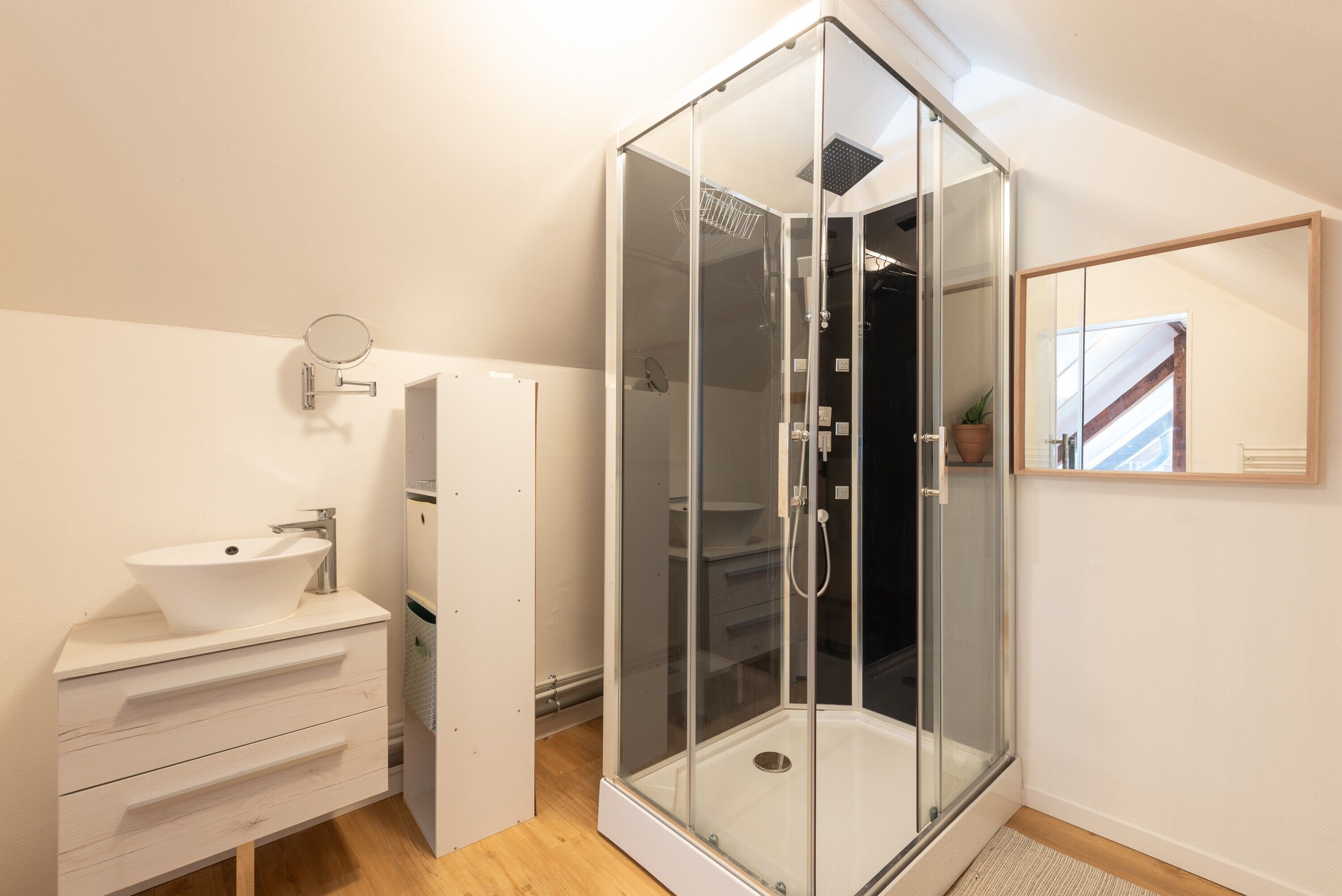 Une salle de bain moderne avec une douche à parois de verre, un lavabo blanc et un miroir.