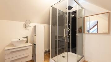 Une salle de bain moderne avec une douche à parois de verre, un lavabo blanc et un miroir.