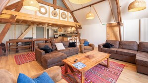 Un vaste espace de vie de style loft, doté de hauts plafonds, de poutres apparentes et d’une grande table à manger.