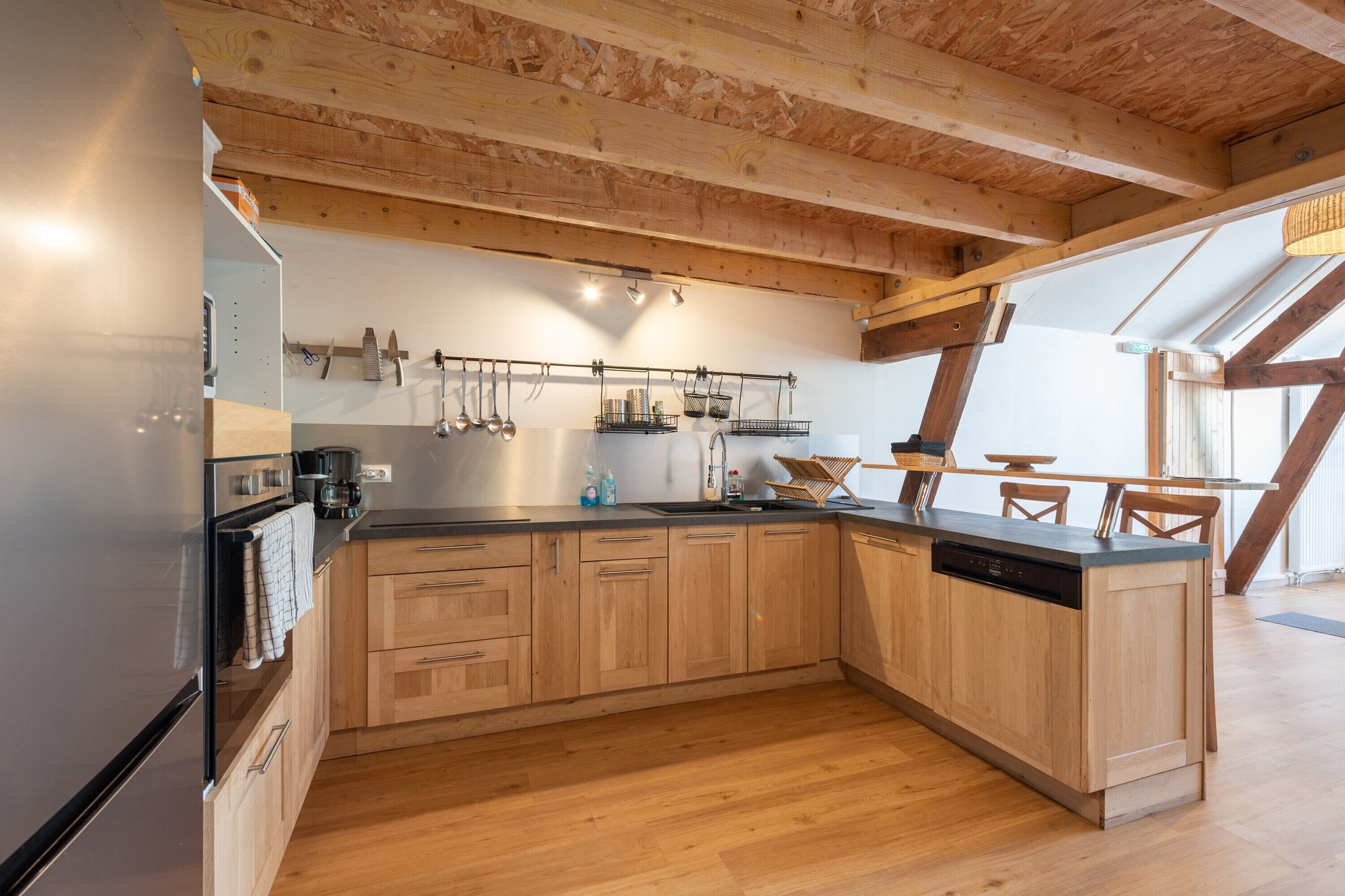 Una cocina moderna con armarios de madera, encimera negra y lavavajillas integrado.