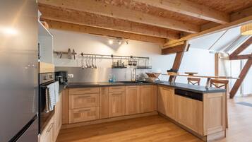 Una cocina moderna con armarios de madera, encimera negra y lavavajillas integrado.