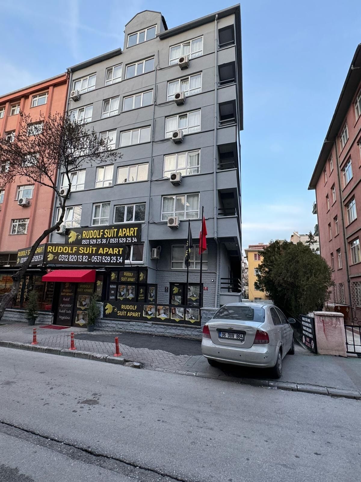 A multi-story building with a sign for 'Rudolf Suit Apart' indicating it is a hotel.